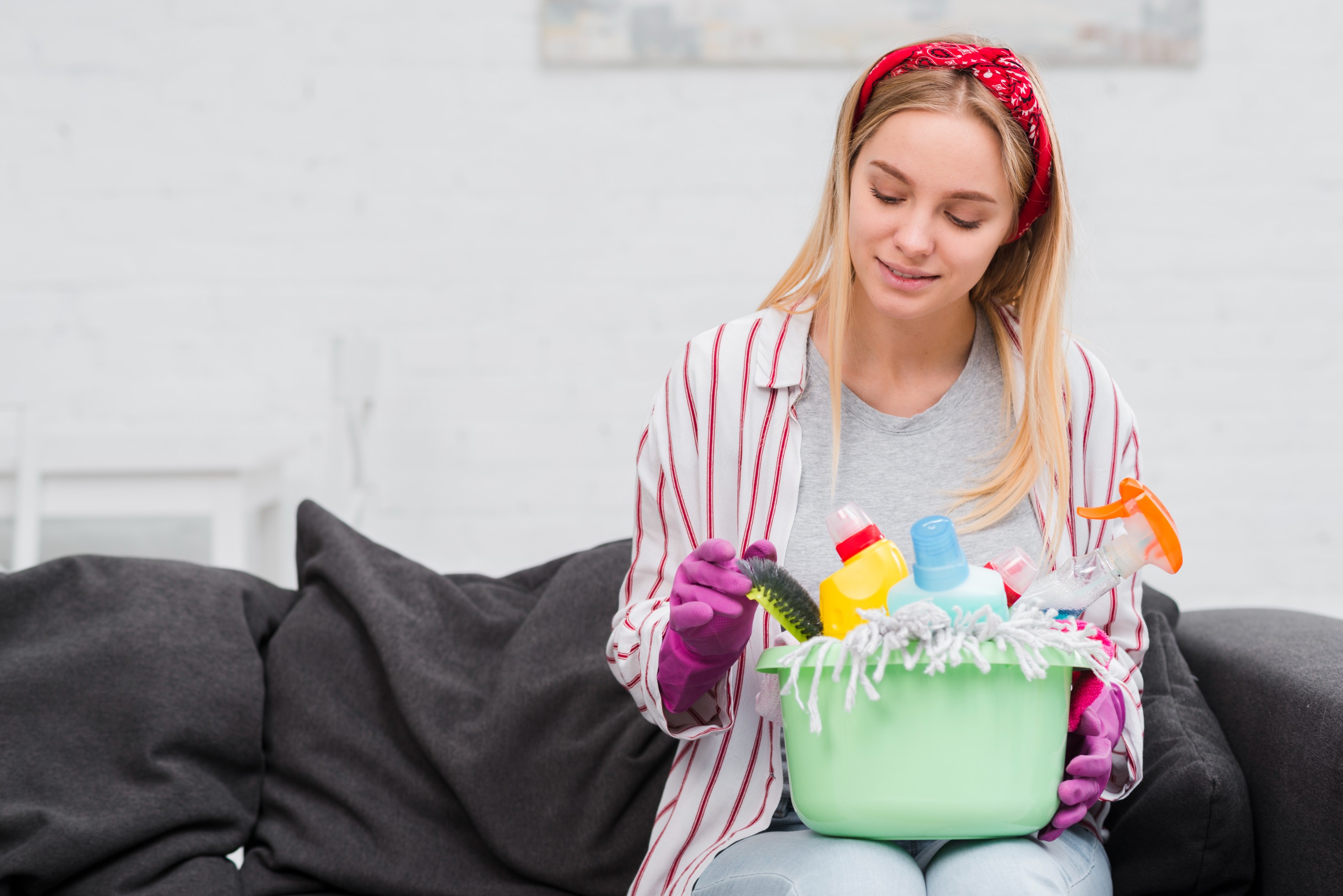 Young woman thoughtfully organizing cleaning supplies at home, symbolizing the mindful process of unclogging physical and emotional clutter for greater calm and mental well-being.