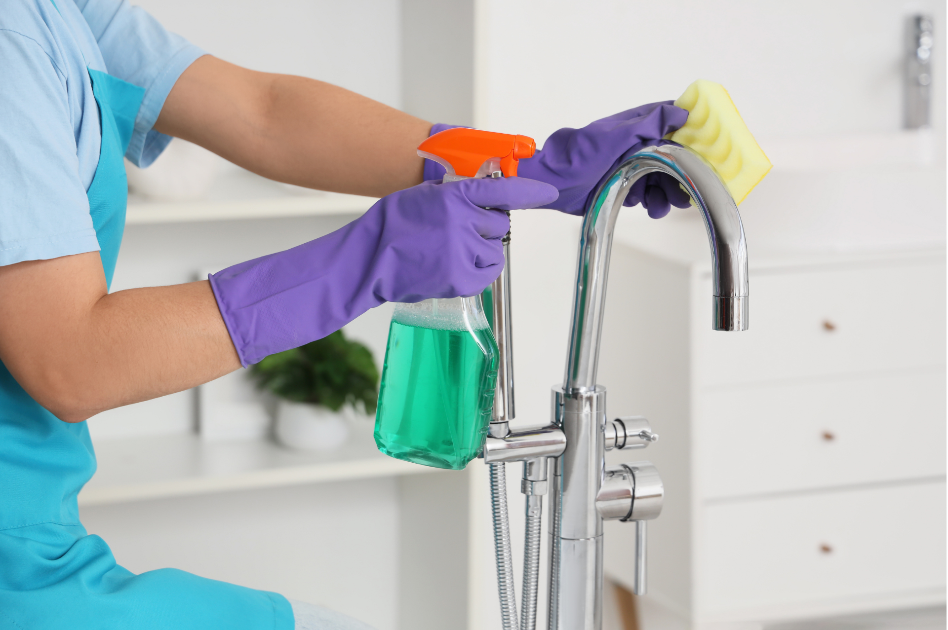Professional cleaner disinfecting kitchen tap during end of tenancy cleaning service in a UK rental property